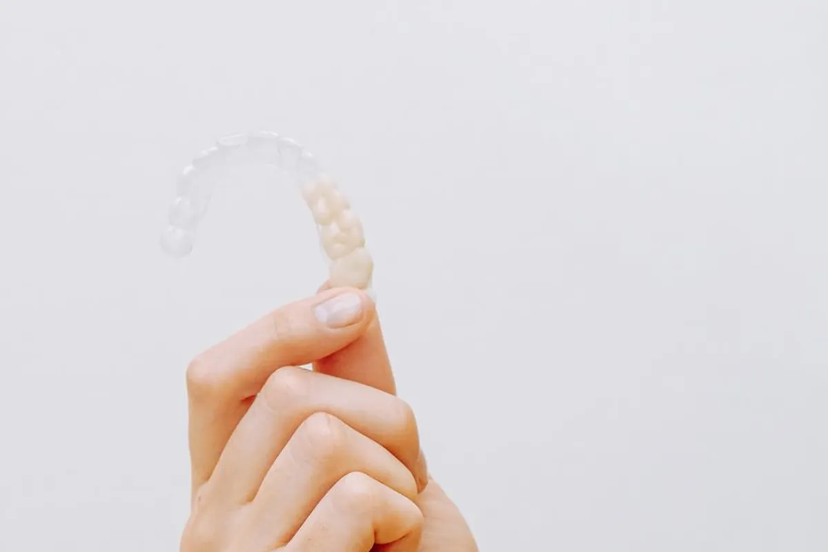Átlátszó Invisalign fogszabályozó sín közelről, kézben tartva