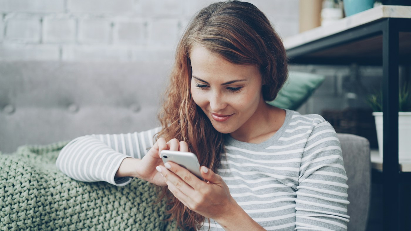 Nő a telefonján olvas, miközben kezelési tapasztalatokról tájékozódik
